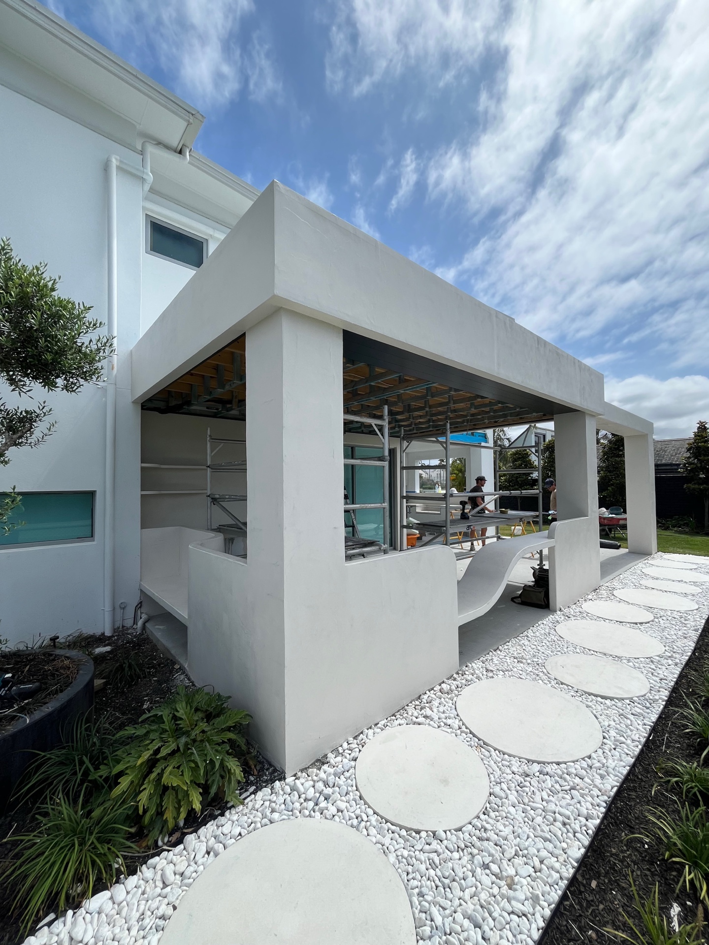 Outdoor pavilion and curved microcement work within an active construction site